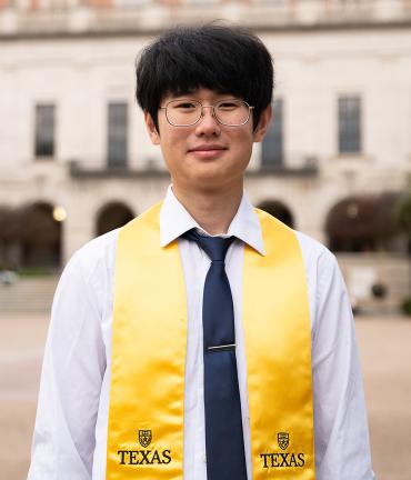 UCSF junior specialist Raymond Sun on UT Austin's campus wearing the yellow Texas graduation sash